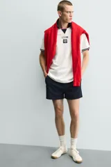 Polo de corte relajado confeccionado en piqué de algodón color blanco. Presenta cuello solapa en color negro con abertura frontal, mangas cortas con ribetes a contraste y estampado conmemorativo USA 94 FIFA World Cup.