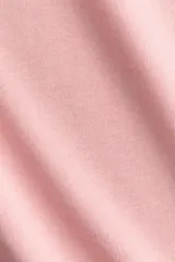Remera oversized de algodón suave, color rosado, con cuello redondo ribeteado y mangas cortas con hombros levemente caídos.