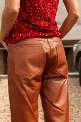 Pantalón de cuero de corte recto y tiro medio, color verde oscuro, con diseño artesanal y botón frontal.
