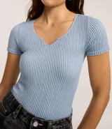 Body de calce ajustado confeccionado en tejido seamless con textura acanalada. Presenta cuello en V, mangas cortas y cierre en la entrepierna.