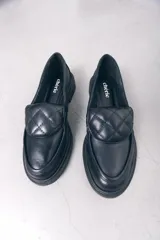 Mocasín de cuero negro con diseño de punta cuadrada y detalle acolchado en la pala. Cuenta con un tacón bajo y cuadrado.