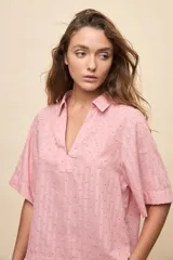 Blusa celeste de manga corta con cuello camisero y escote en V, confeccionada en tejido liviano con textura sutil y estampado de lunares.
