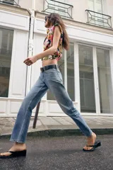 Jeans de tiro medio con corte slim fit, confeccionados en denim azul clásico. Presentan diseño de cinco bolsillos, cierre frontal con cremallera y botón, e incluyen un cinturón negro con hebilla metálica.