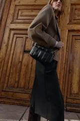 Bandolera mini de diseño acolchado con pespuntes verticales. Cuenta con doble compartimento, uno con cierre imantado y otro con cremallera, además de un bolsillo frontal con cierre imantado. Incluye asa regulable con detalle de cadena metálica.