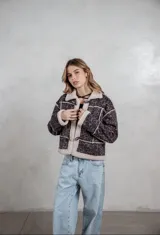 Campera de gamuza con estampado de leopardo en tonos grises, con interior y bordes de corderito sintético color crema. Presenta cierre frontal con botones tipo toggle y diseño de corte recto.