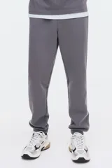 Pantalón deportivo de corte regular, confeccionado en tejido de felpa interlock con interior cepillado. Presenta cintura elástica con cordón de ajuste oculto, bolsillos laterales al bies, un bolsillo trasero insertado y puños acanalados en los tobillos.