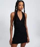 Vestido corto negro con escote profundo, breteles que se atan al cuello y espalda descubierta. Confeccionado en encaje texturizado con forro interno y ruedo con encaje.
