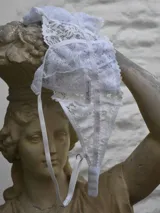 Bralette blanco confeccionado en encaje, con diseño de copas triangulares sin aro ni relleno y tirantes finos regulables.