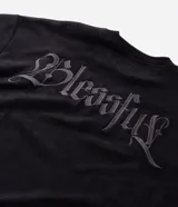 Remera masculina oversize de tejido tipo gamuza sintética (suede) de color negro, con cuello redondo, mangas cortas y detalle de bordado de cruz en el frente.