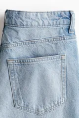 Bermuda de cinco bolsillos en denim de algodón rígido, corte holgado con cierre y botón, lavado claro y detalles de roturas.