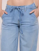 Pantalón tipo jean de corte relajado y pierna ancha, color celeste, con pretina elástica en la espalda, cordón de ajuste frontal y dobladillo en los tobillos.