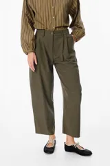 Pantalón de corte sastrero en color verde oliva, con diseño de tiro alto, pinzas frontales y pernera recta de estilo holgado.