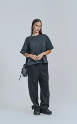 Remera de manga corta color gris oscuro (gris mamba) con calce boxy fit. Presenta un pequeño logo bordado en el pecho.