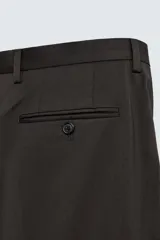 Pantalón de traje regular fit confeccionado en tejido de lana. Presenta bolsillos frontales, bolsillos traseros de vivo con botón y cierre frontal con cremallera y botón.