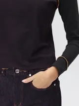 Polera de manga larga confeccionada en tela rib color bordó, con cuello alto y hombreras. Presenta costuras a la vista con pespuntes en hilo de color contrastante en el cuello, puños, hombros y ruedo.