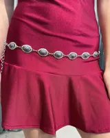 Caderín de metal plateado compuesto por eslabones decorados con piedras circulares de color gris oscuro. Cuenta con cierre de cadena ajustable.