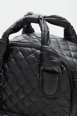 Mochila de diseño acolchado con patrón de rombos, confeccionada en poliamida negra. Cuenta con un compartimento principal con cierre, bolsillo frontal con cierre, bolsillos laterales de red y manijas superiores reforzadas. Incluye un colgante decorativo con la palabra LOVE en letras de carey.
