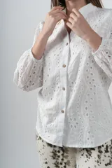 Camisa blanca de algodón con bordados perforados y botones de madera.