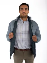 Campera puffer reversible color verde azulado con interior gris. Tiene cuello alto, cierre frontal y bolsillos laterales con cierre.