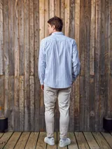 Camisa de manga larga a rayas verticales azules y blancas, con cuello abotonado, bolsillo en el pecho y corte regular.