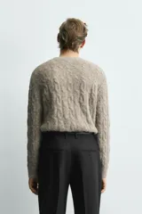 Jersey de punto con acabado cepillado, cuello redondo y manga larga. Presenta un diseño de trenzas verticales en toda la prenda y un corte relajado.