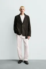 Blazer de corte relajado confeccionada en piel con acabado de ante. Presenta cuello con solapas de muesca, cierre frontal de dos botones, mangas largas y bolsillos de plastrón en la cadera. El diseño no posee forro interior y cuenta con aberturas en la parte trasera.