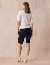 Cárdigan blanco tejido con escote en V, abertura frontal con botones y mangas cortas abullonadas con puño.