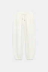 Pantalón jogger de tiro alto color blanco con bolsillos laterales ocultos en costura y cintura elástica ajustable con cordones con punteras metálicas.