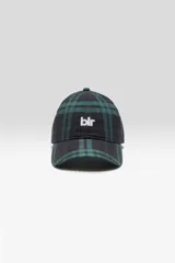 Gorra estilo béisbol de seis paneles con visera curva, confeccionada en tejido con estampado a cuadros en tonos verde oscuro y negro. Cuenta con el logo de la marca bordado en color blanco en el frente y cierre ajustable en la parte trasera.