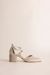 Zapato de tacón bajo color beige, con punta cuadrada, escote en V y tiras cruzadas en el tobillo con hebilla. El tacón es ancho y mide 5 cm.
