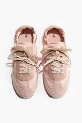 Championes de diseño ligero y femenino en color rosado, con exterior de tela satinada y detalles en gamuza sintética en la puntera y el talón. Cuentan con cordones planos al tono y una suela plana de goma color marrón con textura acanalada.