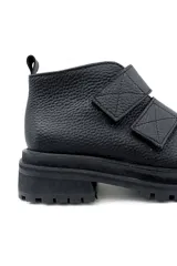 Bota corta negra de cuero con ajuste de velcro y suela track.