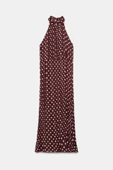 Vestido midi de cuello halter con tejido efecto arrugado y estampado de lunares blancos sobre fondo bordó. Presenta forro interior y cierre en la espalda con cremallera oculta y botones.