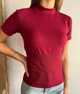 Polera de manga corta color bordó, con cuello alto y diseño ajustado al cuerpo. Presenta una textura acanalada en la zona de la cintura que brinda un ajuste entallado.