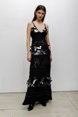 Vestido largo negro con escote en V y tirantes finos. Presenta un diseño de paneles horizontales que alternan bandas de lentejuelas negras brillantes con bandas decoradas con aplicaciones de lentejuelas iridiscentes en forma de pétalos.