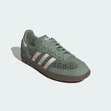 Championes Adidas Samba OG de diseño urbano, con exterior de malla y cuero en tono verde oliva. Presenta las icónicas tres tiras laterales en color crema, talón reforzado y suela de caucho color marrón.