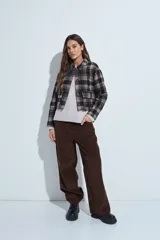 Campera de paño con diseño de cuadros en tonos negro, gris y beige. Presenta cuello camisero, cierre frontal con botones y corte corto.
