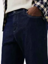 Pantalón de jean azul, corte slim fit, con cierre de botón y cremallera.