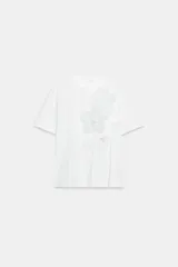 Camiseta blanca de algodón con cuello redondo y manga corta, destacada por aplicación de flores tridimensionales a tono en el frente.