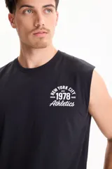 Musculosa negra de algodón, con diseño sin mangas y estampado gráfico blanco en la espalda con texto y números deportivos estilo universitario.