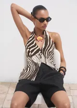 Chaleco tipo peplum con estampado de cebra en tonos marrón y blanco, cuello halter y cierre frontal con botones.