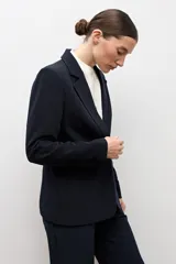 Blazer clásico color negro de corte entallado, con solapa de muesca, cierre de un botón frontal y bolsillos de ojal en los laterales.