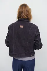 Chaqueta de pana color azul oscuro, con cuello camisero, cierre frontal con botones y bolsillos laterales. Diseño de corte recto y manga larga.