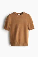 Sweater de punto suave con ajuste entallado, cuello redondo y mangas cortas. Presenta terminaciones acanaladas en cuello, puños y bajo.