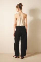 Jean de tiro medio-alto, color negro, de calce holgado con piernas anchas que se estrechan hacia el tobillo. Presenta pinzas en las rodillas que acentúan su forma "balloon" y un recorte lateral. Confeccionado en denim rígido con lavado suavizado, cierre y botón.