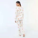 Pijama de dos piezas compuesto por una remera de manga larga y pantalón largo, confeccionado en algodón color blanco con estampado de Winnie the Pooh y corazones rojos.
