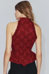 Corset bordó de cuello halter con hombros descubiertos, confeccionado con combinación de tejidos con patrón floral, detalles de volados en las sisas y bajo en peplum. Cuenta con cierre en la espalda con cremallera.