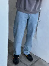 Jean azul claro de corte amplio, estilo carpintero, con pespuntes en contraste y cierre en el tobillo.