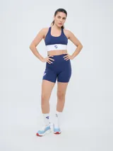 Top deportivo de mujer Umbro del Club Nacional de Football, modelo Nina. Diseño en color azul marino con banda elástica inferior en color blanco y el escudo oficial del club al centro.