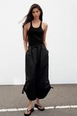 Pantalón culotte de tiro medio, color verde militar, con cintura elástica y bolsillos laterales ocultos. Presenta un diseño de bajo ancho con aberturas ajustables mediante cordones fruncidos en los laterales.